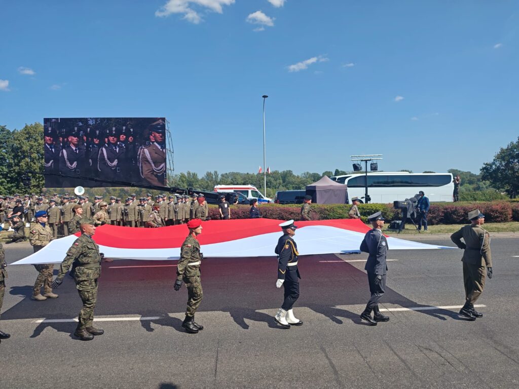Żołnierze niosą dużą polską flagę podczas defilady