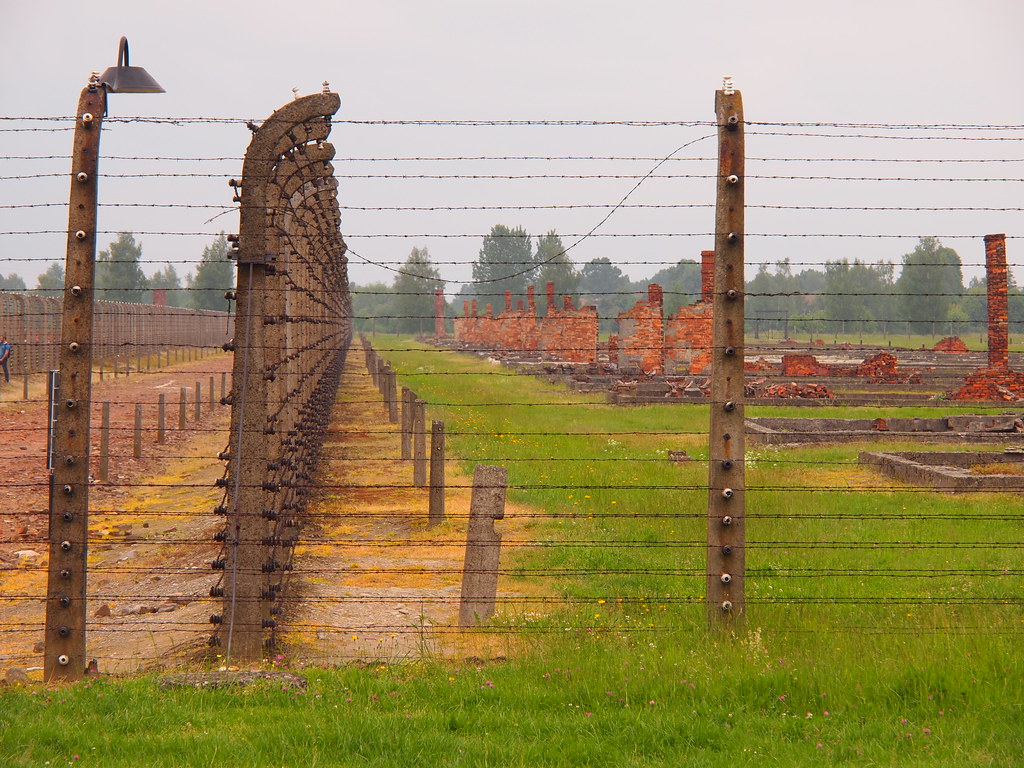 Ogrodzenie z drutu kolczastego i pozostałości zabudowań byłego obozu Auschwitz-Birkenau
