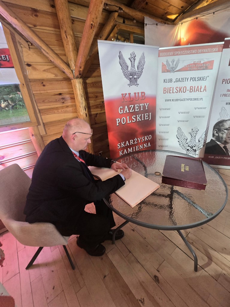 Bogdan Święczkowski wpisuje się do księgi przy banerach klubów