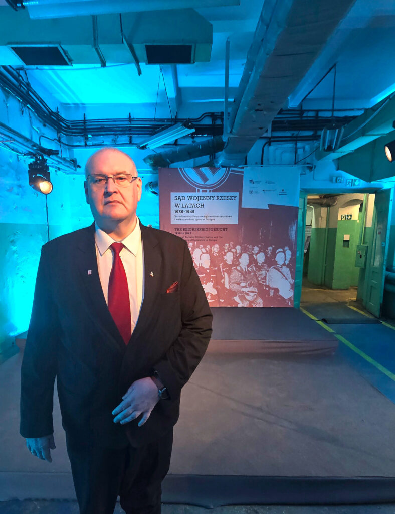 Bogdan Święczkowski przy planszy z tytułem wystawy o Sądzie Wojennym Rzeszy