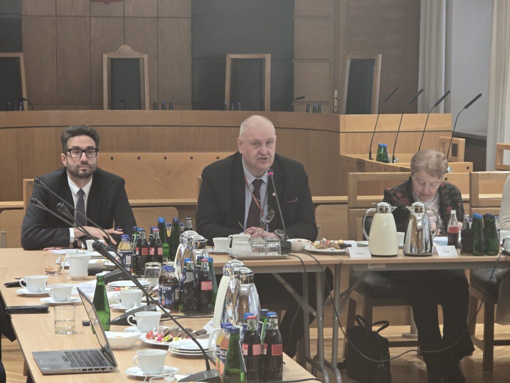 Bogdan Święczkowski przemawia przy stole podczas debaty w TK