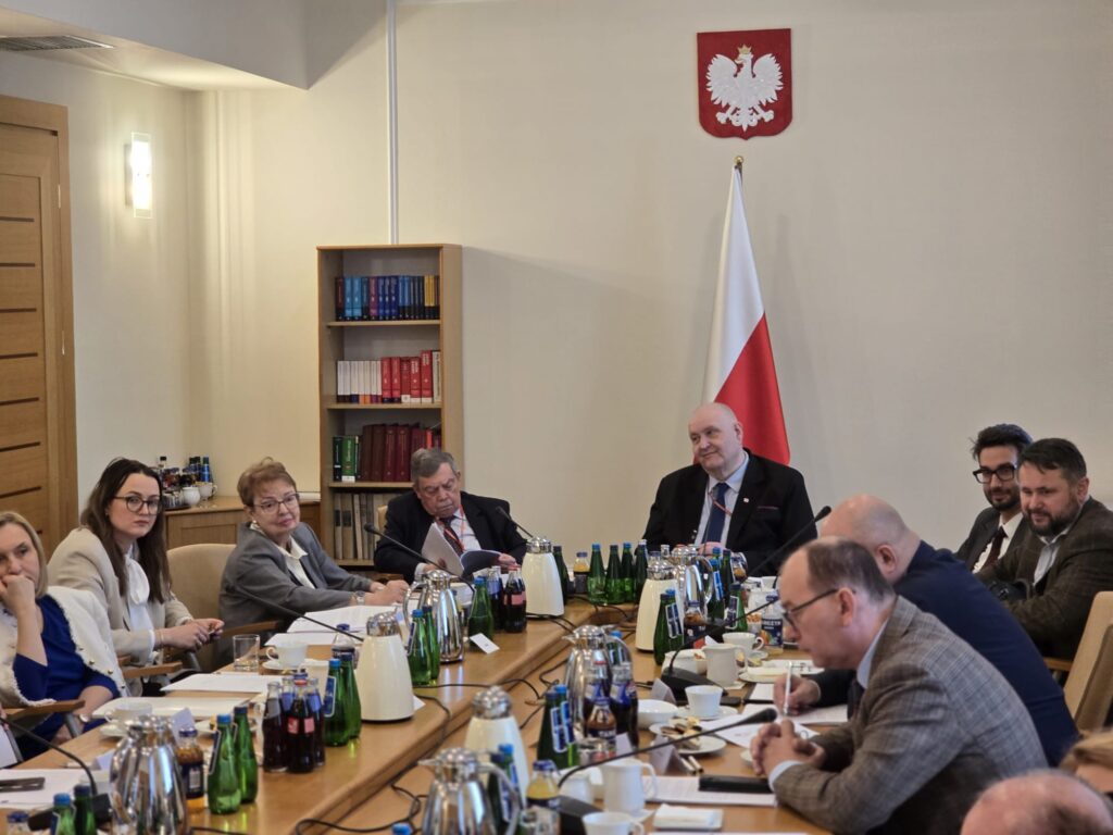 Uczestnicy debaty siedzą przy stole w siedzibie TK