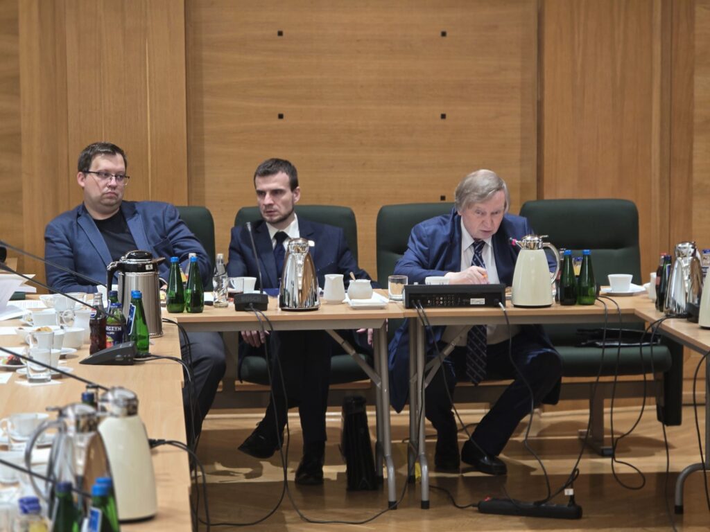 Uczestnicy debaty przy stole w sali TK