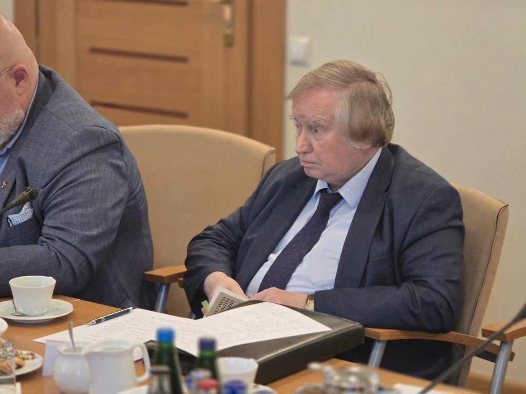 Uczestnik dyskusji siedzi przy stole z notatkami