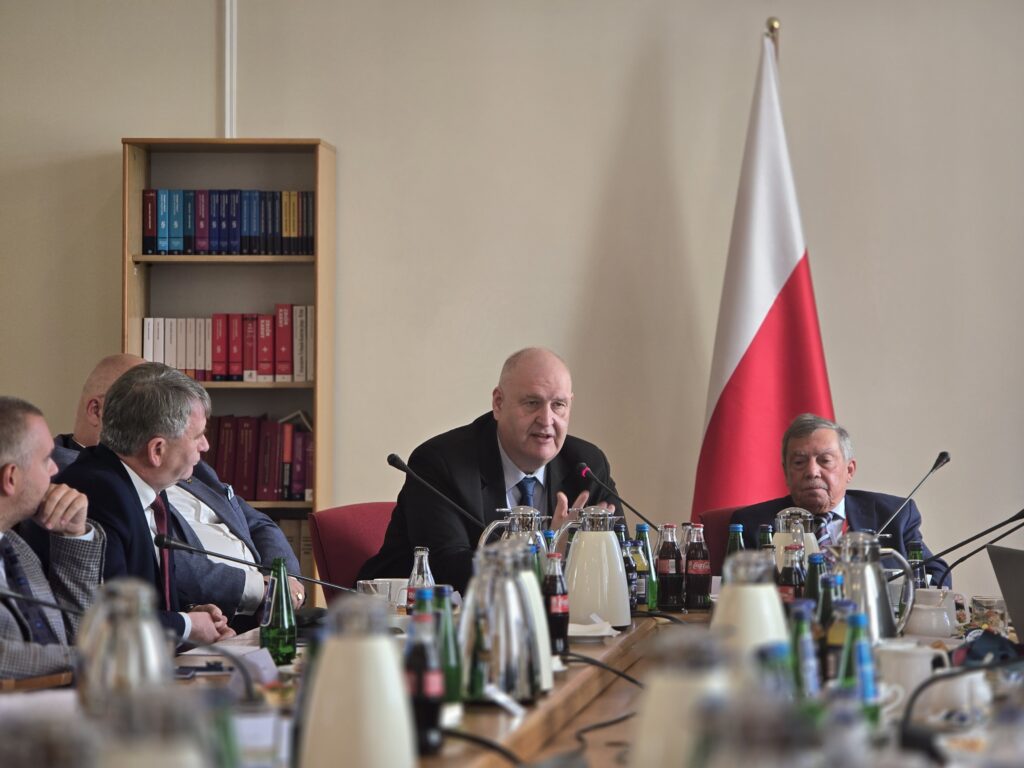 Bogdan Święczkowski przemawia podczas spotkania przy stole