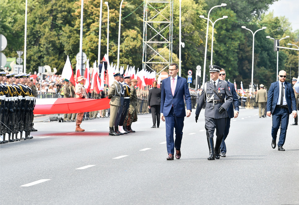 Premier Mateusz Morawiecki przechodzi obok żołnierzy i pocztów sztandarowych na Wisłostradzie