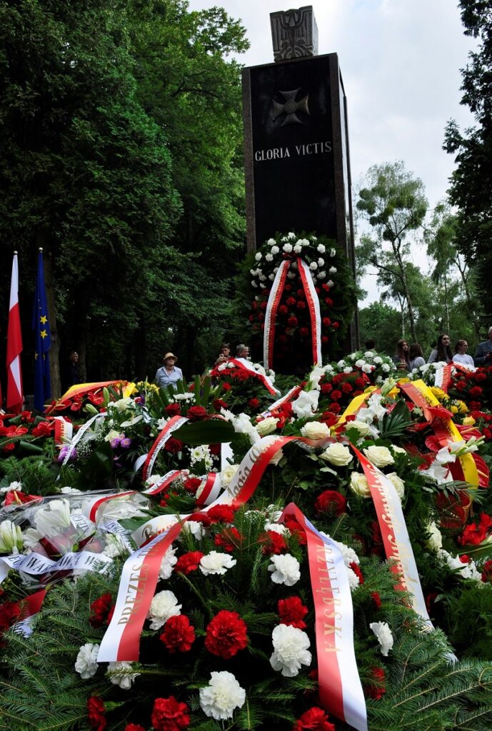Pomnik Gloria Victis otoczony wieńcami i biało-czerwonymi szarfami