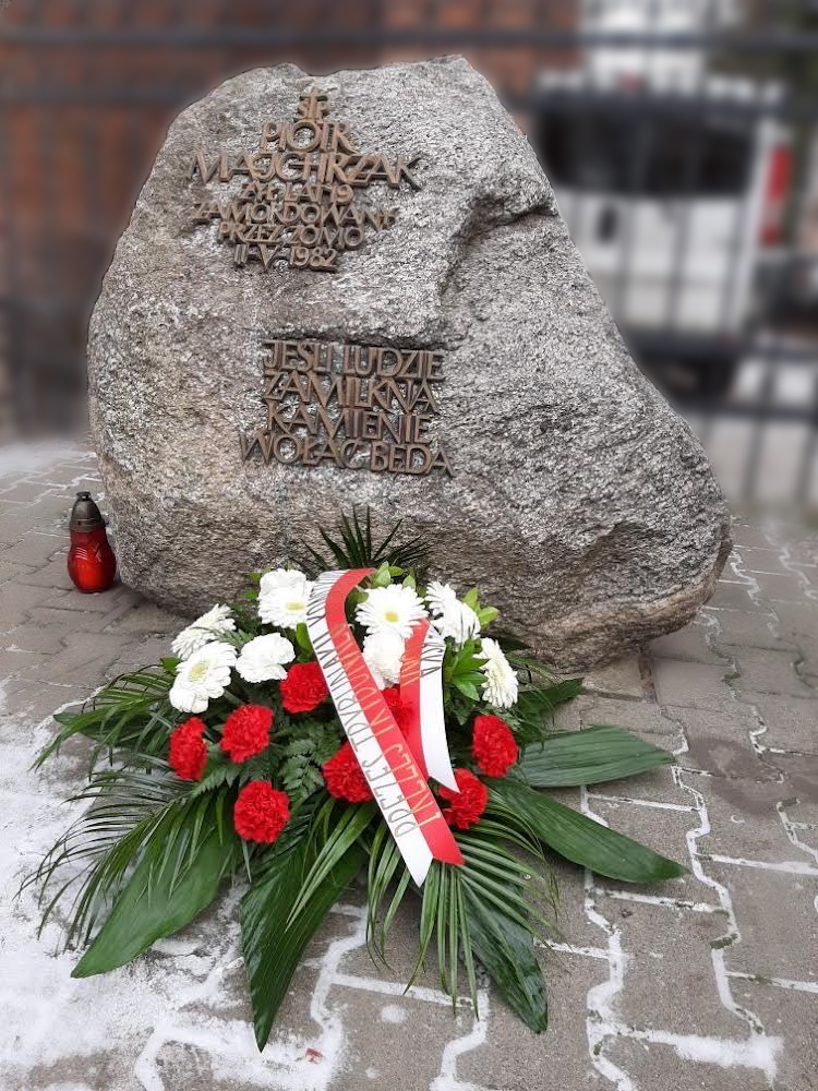 Kamień upamiętniający Piotra Majchrzaka oraz biało-czerwony wieniec