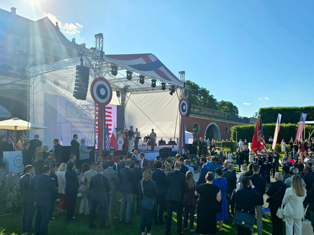 Goście uroczystości i scena z flagami USA w ogrodach Zamku Królewskiego