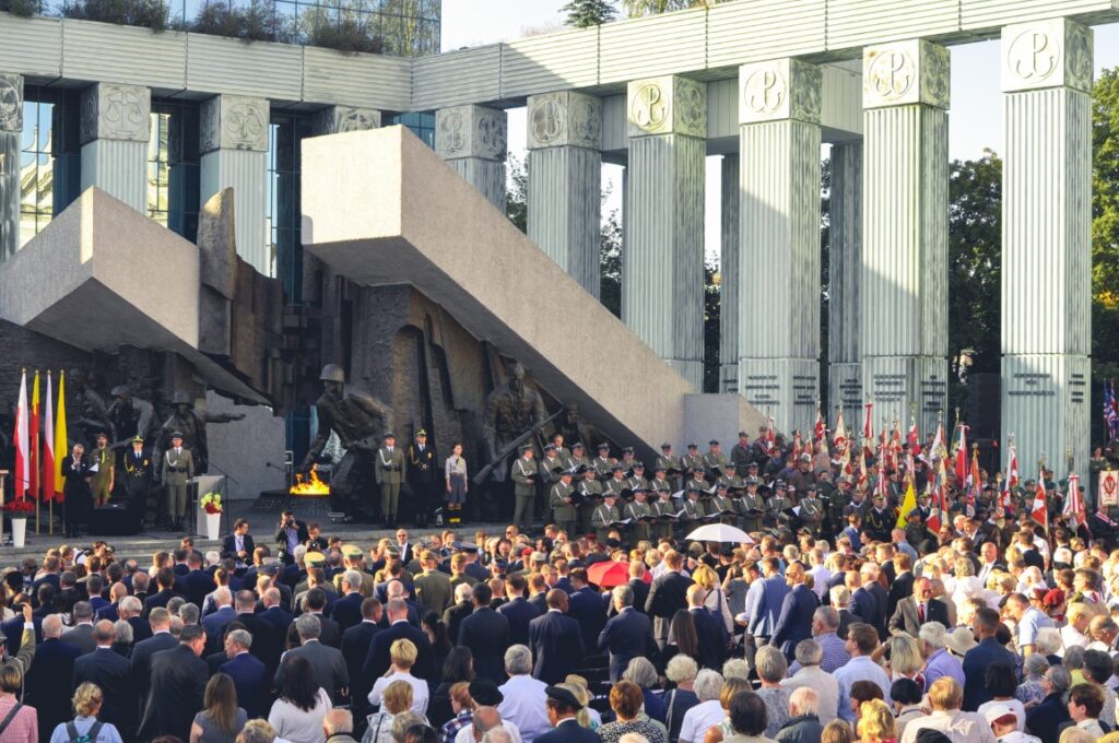 Uczestnicy uroczystości i poczty sztandarowe przed pomnikiem Powstania Warszawskiego