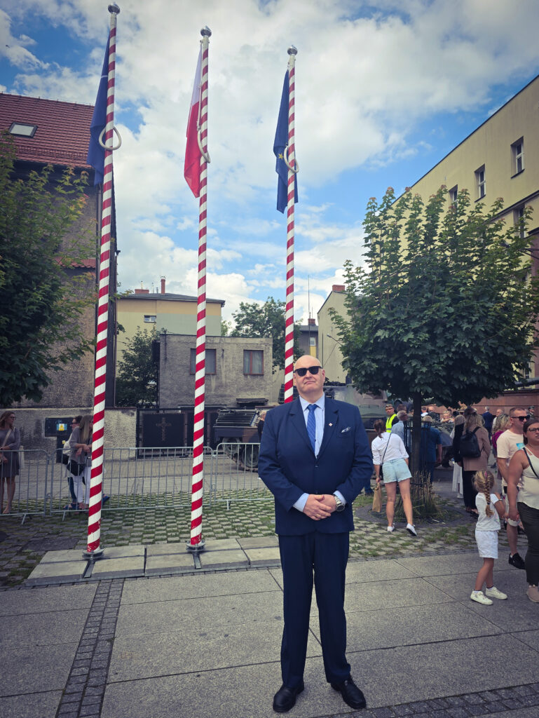 Bogdan Święczkowski przed masztami z flagami